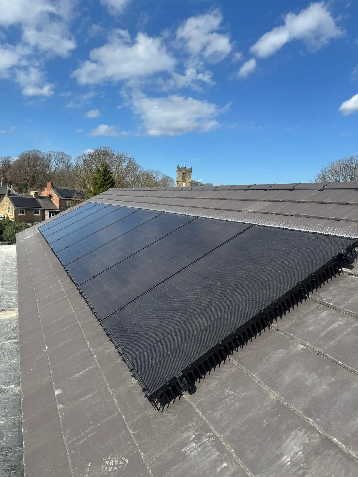 Solar panel side guards and spikes installed on an office roof to stop pigeons nesting under the panels